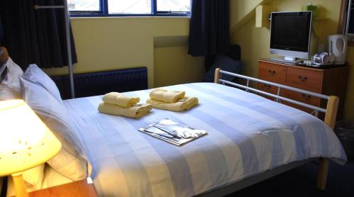 a bedroom with a bed with towels and a tv at Adam Place Guest House in Windermere