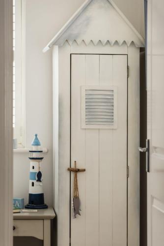 a white door with a lighthouse next to a table at Half Moon in Camber