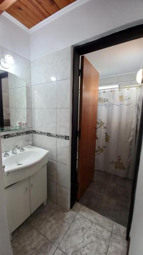 y baño con lavabo y ducha con espejo. en Complejo Quimpe en Villa Giardino