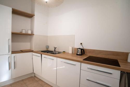 une cuisine avec des armoires blanches et un évier dans l'établissement Appartement 55m² - 2/4 personnes en centre ville, à Bollène
