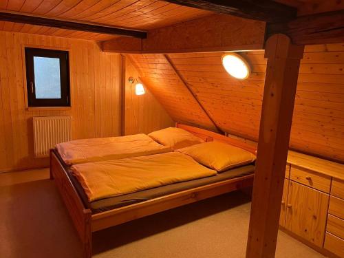 a bed in a wooden room with two pillows at Venkovská chalupa in Jestrabi V Krkonosich