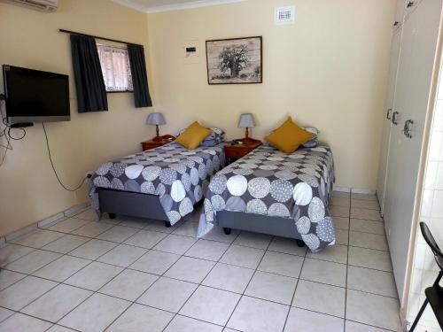 a room with two beds and a tv in it at Anne's Cottage in Durban