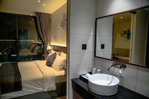 a bathroom with a sink and a bed with a mirror at Apec Mandala Sun-Condotel Phu Yen in Tuy Hoa