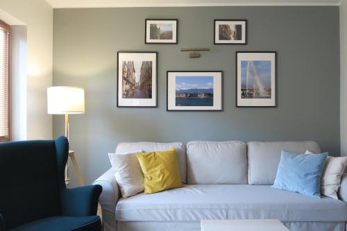 Apartament Geneva في وارسو: غرفة معيشة مع أريكة بيضاء والصور على الحائط