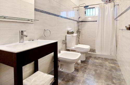 a white bathroom with a toilet and a sink at Puertas De La Serena in La Paloma
