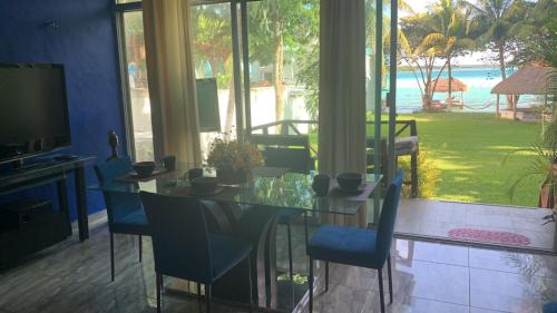 a dining room with a glass table and blue chairs at Casa Tarimoro-Bacalar in Bacalar
