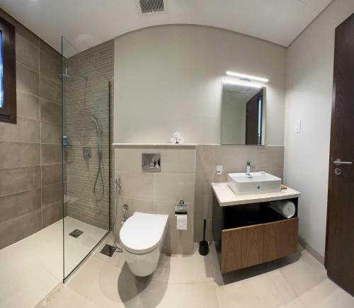 een badkamer met een toilet, een wastafel en een douche bij Beach front Le Bon villa in Muscat