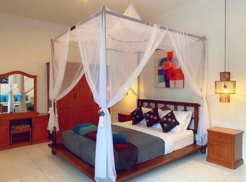 Villa Cantik Kuta Regency في كوتا: غرفة نوم بسرير مع مظلة