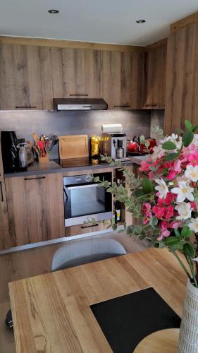 a kitchen with wooden cabinets and a vase of flowers at Le Soladret - 2 pièces 4 étoiles - Vue extraordinaire sur les Aravis in La Clusaz