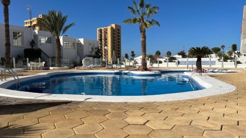 uma grande piscina com palmeiras e edifícios em Boutique studio, sea views of Las Vistas and free wifi em Playa de las Americas