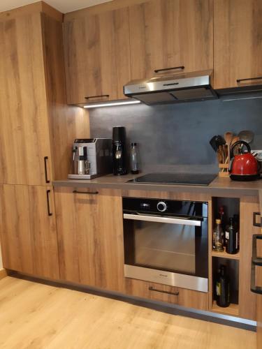 a kitchen with wooden cabinets and a stove top oven at Le Soladret - 2 pièces 4 étoiles - Vue extraordinaire sur les Aravis in La Clusaz