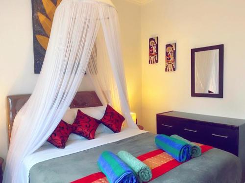 a bedroom with a canopy bed with pillows at Villa Cantik Kuta Regency in Kuta