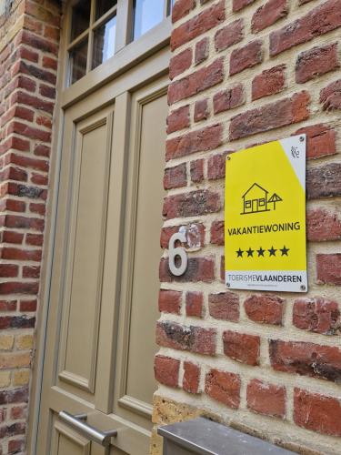 znak na boku ceglanego budynku z znakiem ostrzegawczym w obiekcie Poortershuys w mieście Ypres