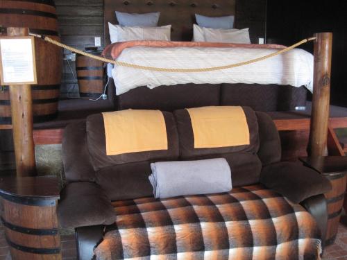 a bedroom with a bed and a ottoman at Blue Roan Country Lodge in Vlakfontein