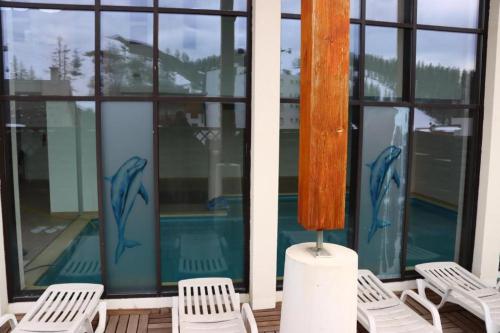 - un ensemble de chaises blanches assises sur une terrasse couverte avec fenêtres dans l'établissement Charmant 2 pièces centre station, à Valberg