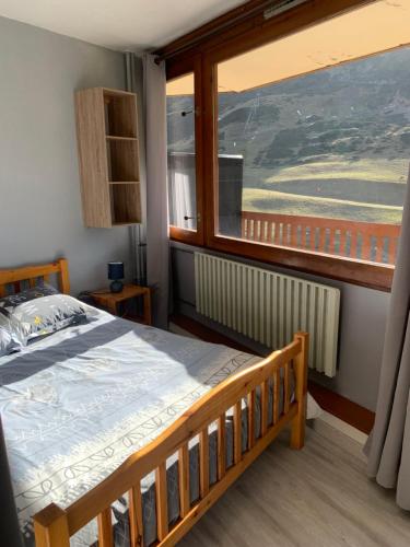 Un dormitorio con una cama y una ventana grande. en La Mongie Superbe vue Pieds des pistes, en La Mongie
