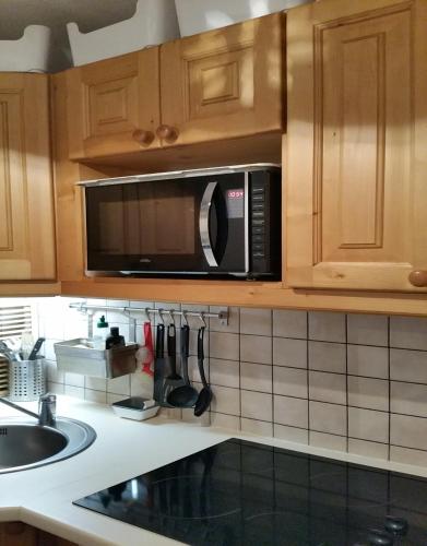 - une cuisine avec un four micro-ondes au-dessus d'un évier dans l'établissement Le Skisun - Massif et Parc national des Ecrins - Puy Saint Vincent 1800, à Puy-Saint-Vincent