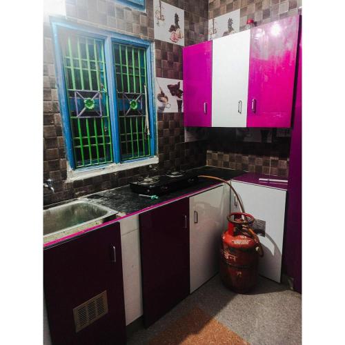 a kitchen with pink and blue cabinets and a sink at Sai Homestay in Kanchipuram