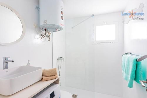 biała łazienka z umywalką i lustrem w obiekcie Vivienda Vacacional Casa Las Cucharas w Costa Teguise