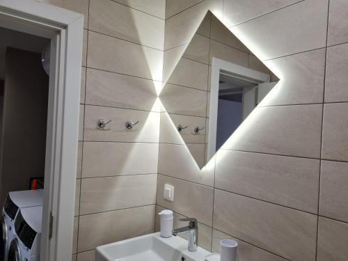uma casa de banho com um lavatório e um espelho na parede em Чудесен нов апартамент Илинден em Varna City
