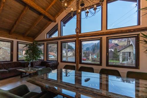 a large room with a table and a bunch of windows at Ranger Chalet in Moieciu de Sus