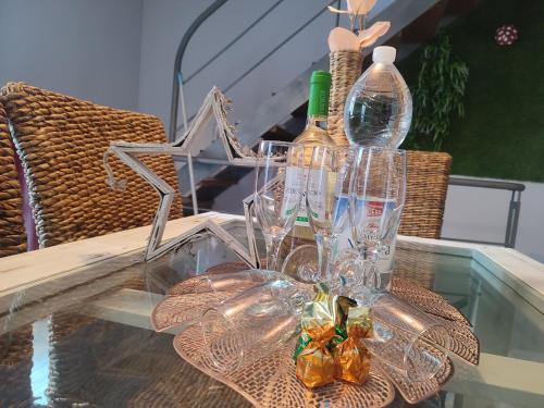 a glass table with wine glasses and bottles on it at Encanto. Céntrico tríplex cerca de la Corredera y casco antiguo. in Córdoba