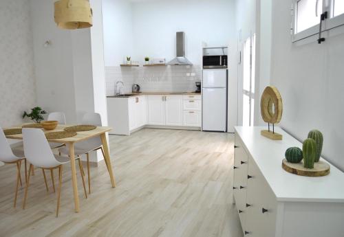 a white kitchen with a table and a dining room at Loft Sol y Luna en Las Palmas de Gran Canaria in Las Palmas de Gran Canaria