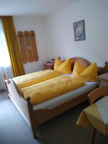 a bedroom with a wooden bed with yellow sheets and pillows at Haus Traudl in Mayrhofen