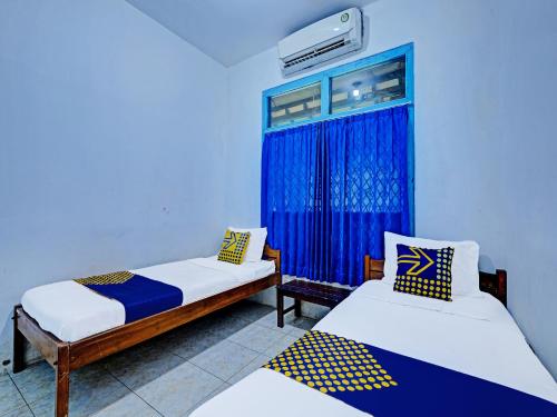 een kamer met 2 bedden en een raam bij SPOT ON 2275 Omah Jm in Beran-kidul