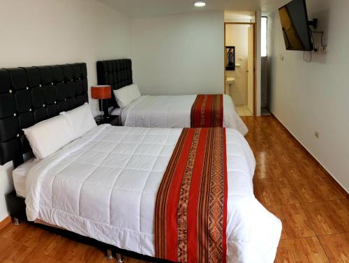 una camera con 2 letti e una TV a schermo piatto di Hostal Cusco de mis Sueños a Cuzco