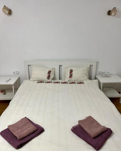 a white bed with two towels on top of it at Casuta de la Munte in Sfodea