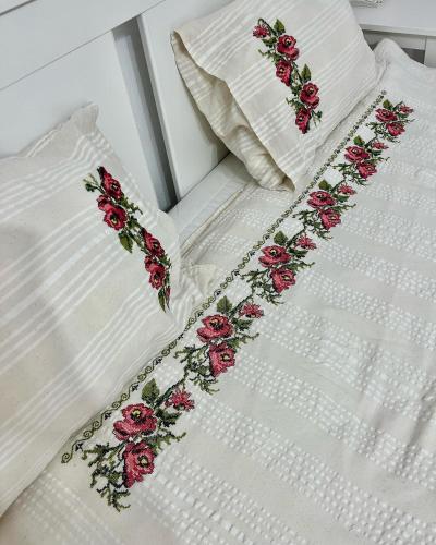 a white bed with red flowers embroidered on it at Casuta de la Munte in Sfodea