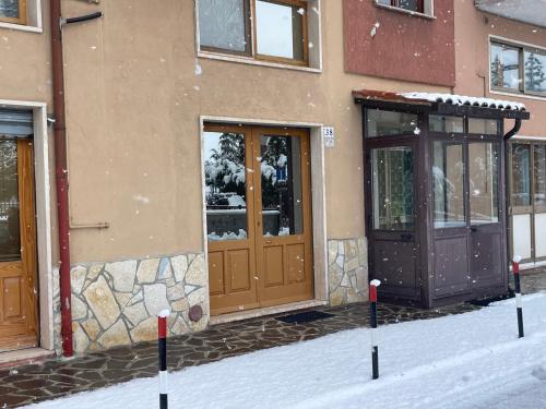 ロッカラーゾにあるResidenza MareaCasaの雪中の木の扉のある建物