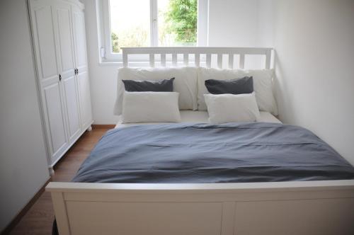 Bett in einem weißen Zimmer mit 2 Kissen in der Unterkunft RELAX Apartment mit Garten - Lifestyle am Bodensee, Fahrräder inklusive in Bregenz
