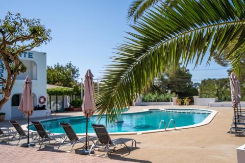 a swimming pool with chairs and umbrellas at Apartamentos Barbarroja - Formentera Break in Playa Migjorn