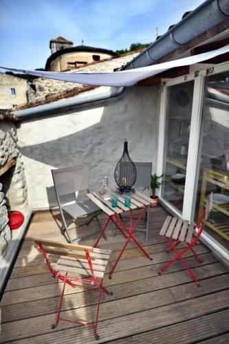 un patio avec une table et des chaises sur une terrasse dans l'établissement Gîte Appartement dans maison de village, à Labeaume
