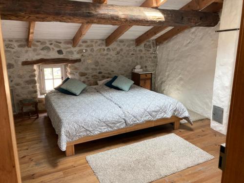 - une chambre avec un lit dans une pièce dotée de murs en pierre dans l'établissement Gîte Appartement dans maison de village, à Labeaume