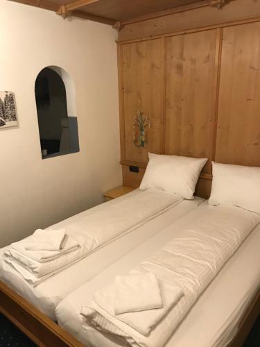 a large bed with white pillows in a room at Brenners Dorfstube in Fieberbrunn
