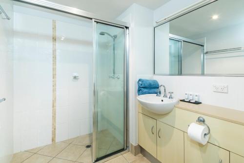 a bathroom with a glass shower and a sink at Stunning Penthouse at Mcleod Street in Cairns