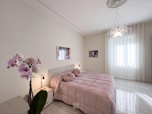 ein Schlafzimmer mit einem rosa Bett und einer Blumenvase in der Unterkunft Emma Home Matera in Matera