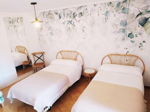 2 camas en una habitación con una pared floral en Mirador Palacios- céntrico con vistas en Albarracín