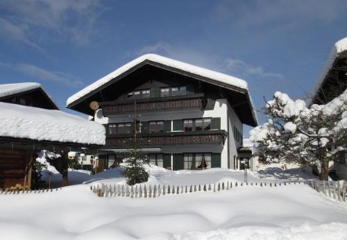 a house covered in snow with a fence at Gästehaus Rappenkopf in Oberstdorf