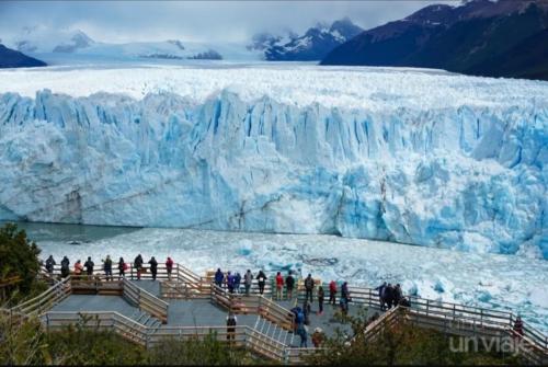 un grupo de personas de pie frente a un glaciar en Cba en El Calafate