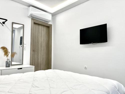 um quarto branco com uma cama e uma televisão de ecrã plano em ενtreé guest house near Palamidi Castle em Nafplio