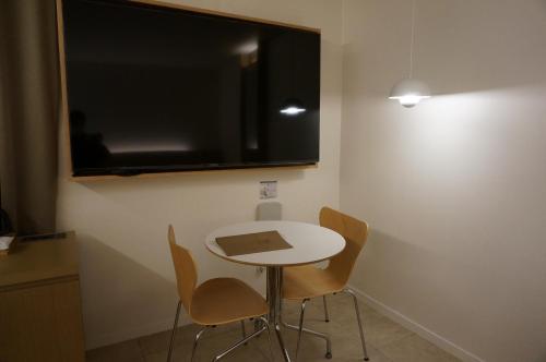 a small table and chairs in a room with a tv at Sodo Hotel Paju in Paju