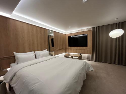 a bedroom with a large white bed and a flat screen tv at Sodo Hotel Paju in Paju
