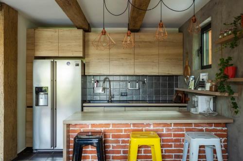 a kitchen with a refrigerator and two yellow stools at Kežman Mountain Houses in Kopaonik