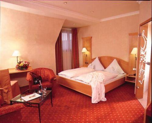 Bad Rippoldsau-SchapbachにあるHotel Restaurant Ochsenwirtshofのベッドとテーブルが備わるホテルルームです。