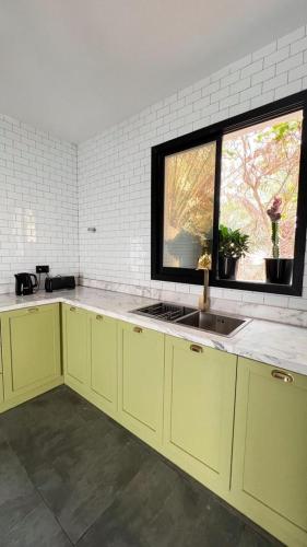 a kitchen with yellow cabinets and a sink and a window at Two Palm - Villa in Ras al Khaimah