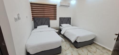 two beds in a room with white sheets at Nabateans Home Hotel in Wadi Musa